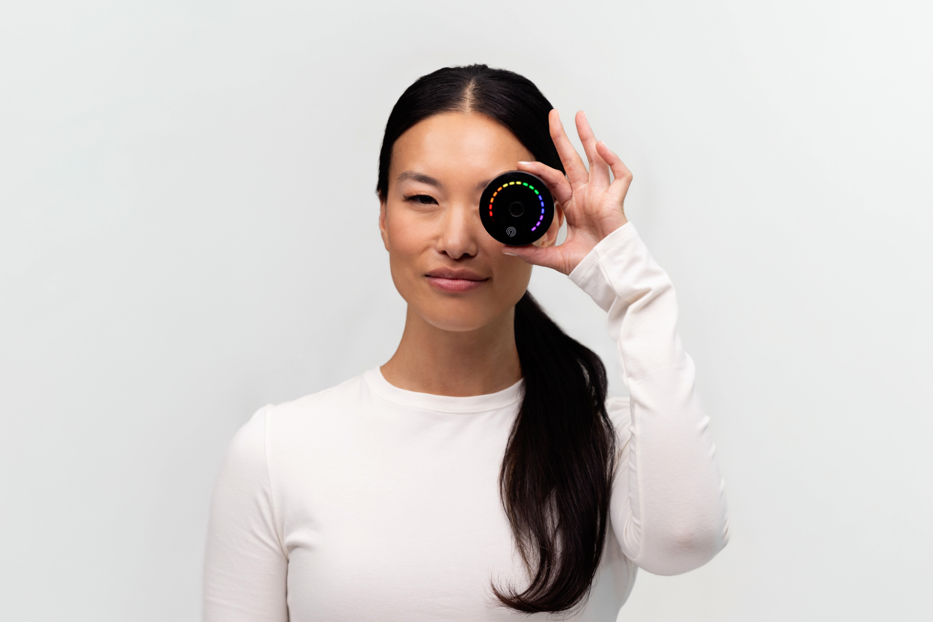 A lady holding the PRYSM iO machine up to her eye